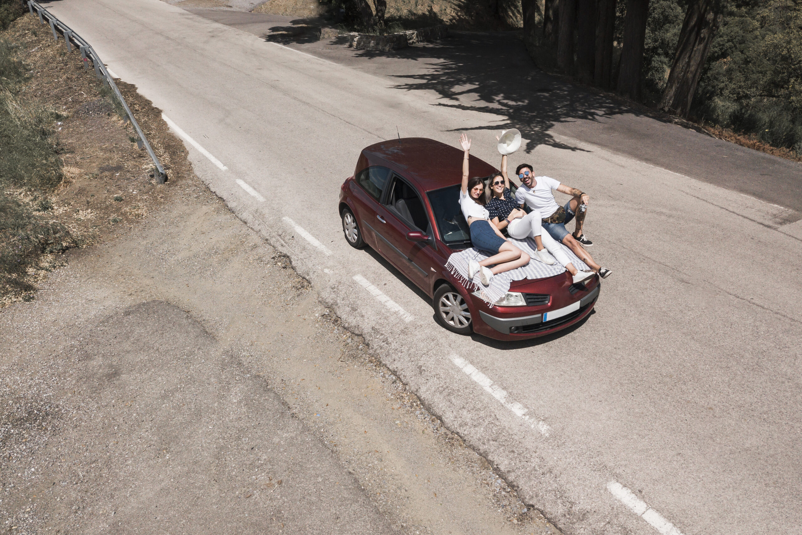 three friends sitting car hood enjoying trip